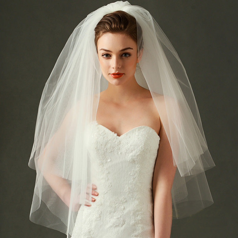 Bride wearing the Juliette classic short bridal veil with layered sheer mesh and a white strapless wedding gown