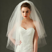 Bride wearing the Juliette classic short bridal veil with layered sheer mesh and a white strapless wedding gown