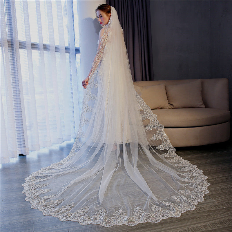 Bride wearing the Celestine long lace wedding veil beside a window