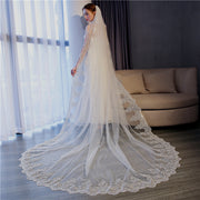 Bride wearing the Celestine long lace wedding veil beside a window