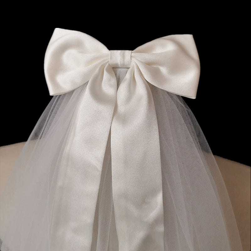 Close-up of the Colette oversized satin-style bridal bow with soft mesh veil and flowing ribbon tails