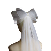 Noelle sheer white bridal veil with an oversized structured bow displayed on a dress form