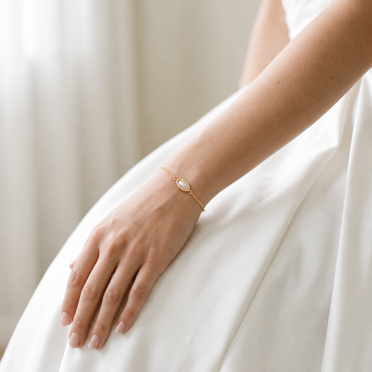 Bride wearing the Margot delicate gold-tone bracelet with an oval centerpiece against an ivory wedding dress