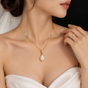 Model wearing the Clara gold-tone pearl drop pendant necklace with a white bridal dress