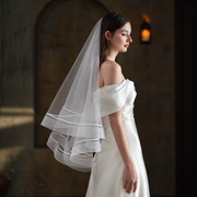 Bride in warm chapel light wearing the Celeste satin-trim double-layer veil