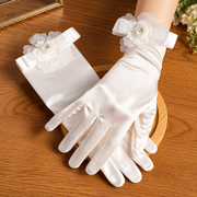 White satin bridal gloves arranged on a wooden surface