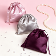 Satin drawstring gift pouches displayed with pearls