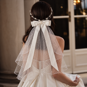 Back view of a bride wearing the Colette satin-style bow veil with flowing ribbons in an indoor bridal setting