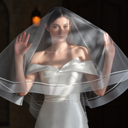 Bride wearing the Celeste satin-trim double-layer veil in warm amber light