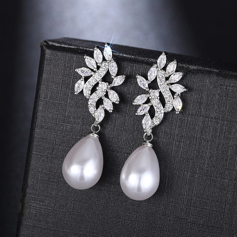 Pair of Elodie pearl drop earrings displayed on a black jewelry box