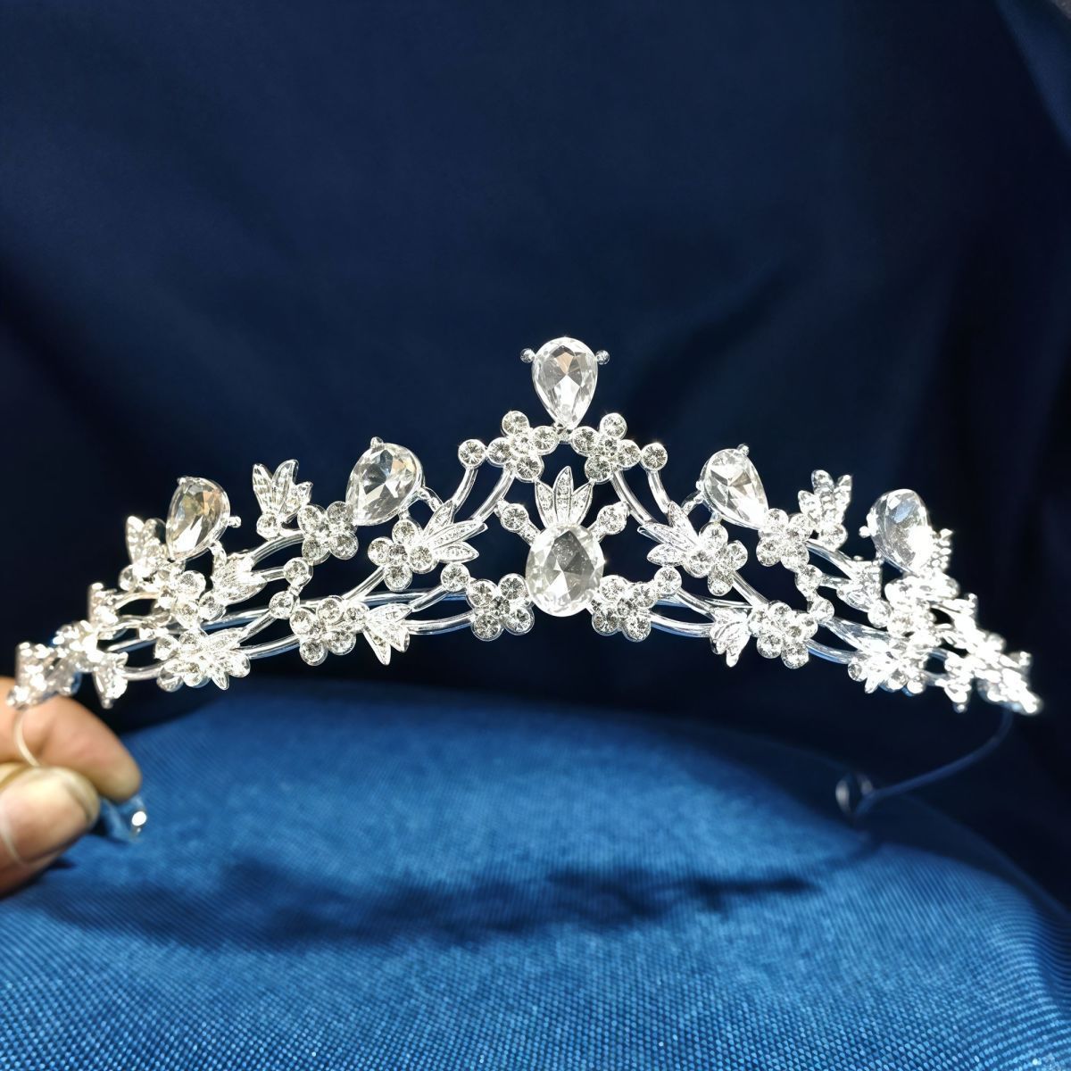 Close-up of the Adeline floral crystal bridal crown with silver-tone branches and rhinestone decorations against blue fabric