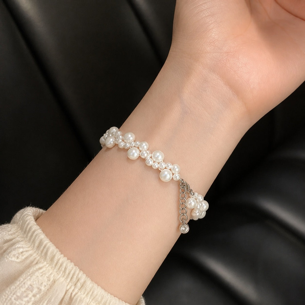 Close-up of Rosalie floral pearl bracelet styled on wrist with a cream knit sleeve