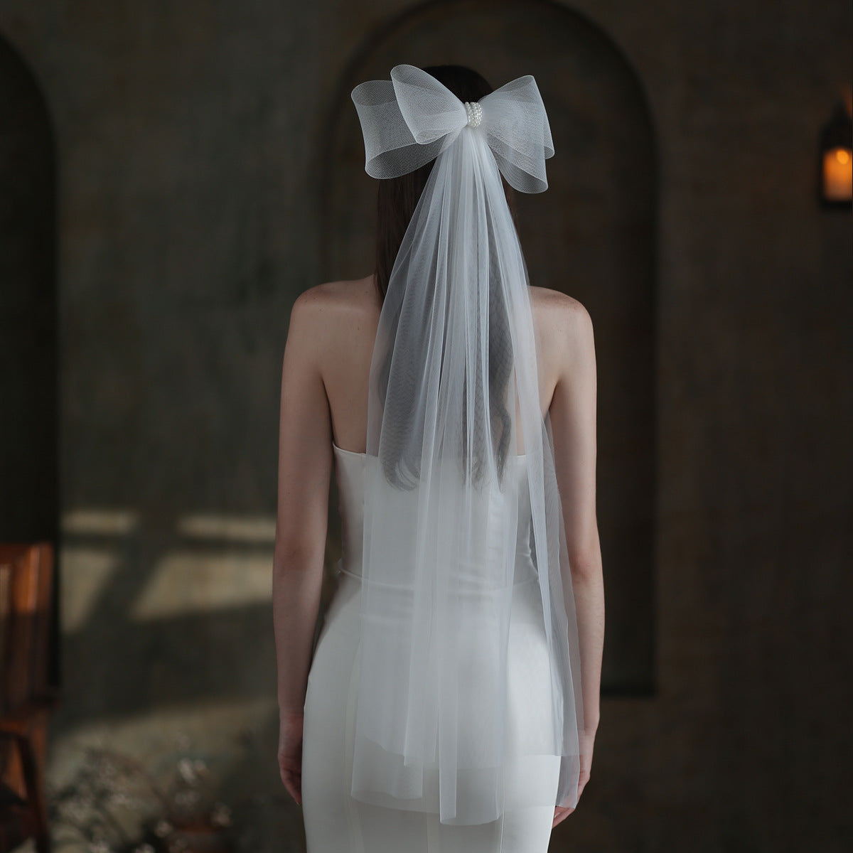 Back view of a bride wearing the Noelle white bow bridal veil with a long sheer drape