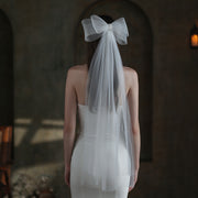 Back view of a bride wearing the Noelle white bow bridal veil with a long sheer drape