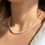 Close-up of the Audrey white faux pearl necklace styled with an elegant neckline
