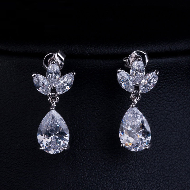Isla dangling teardrop clip on earrings with sparkling leaf-shaped stones on a dark background