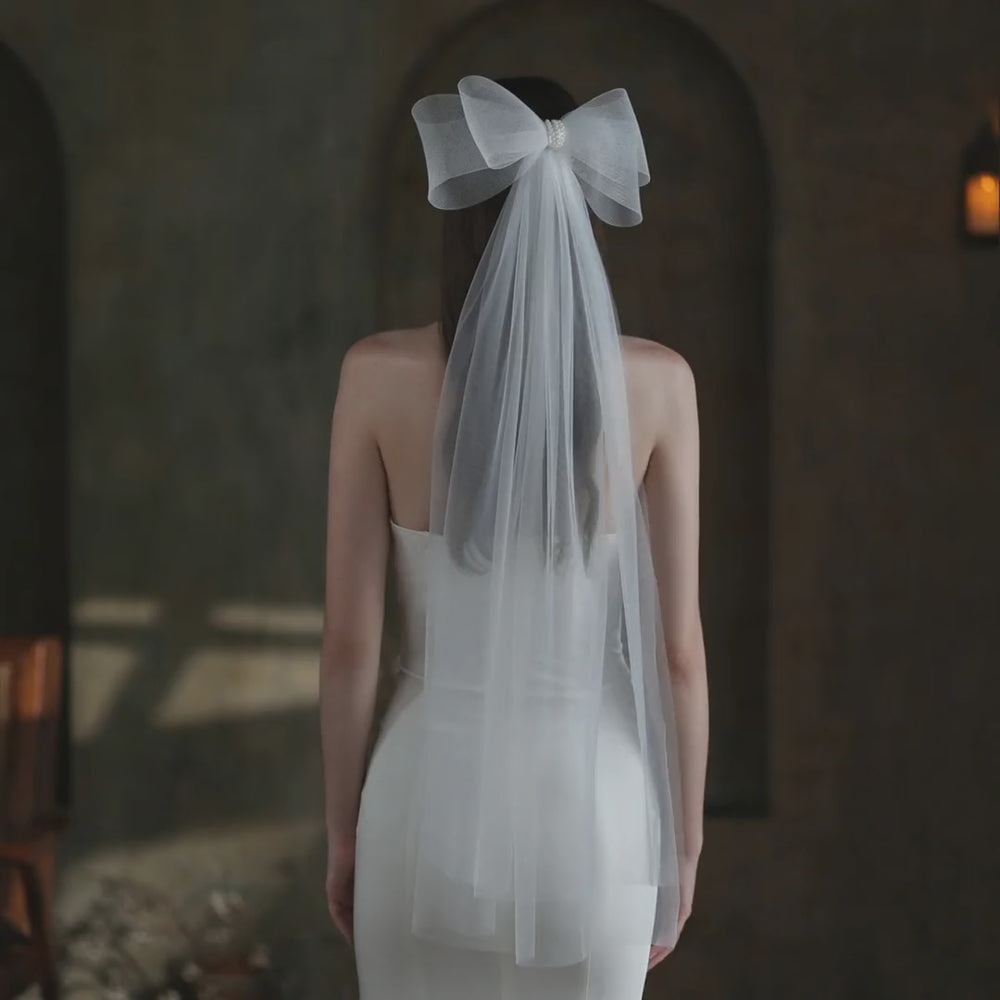 Model wearing the Noelle Sheer Bow bridal veil, showing the bow and sheer fabric.