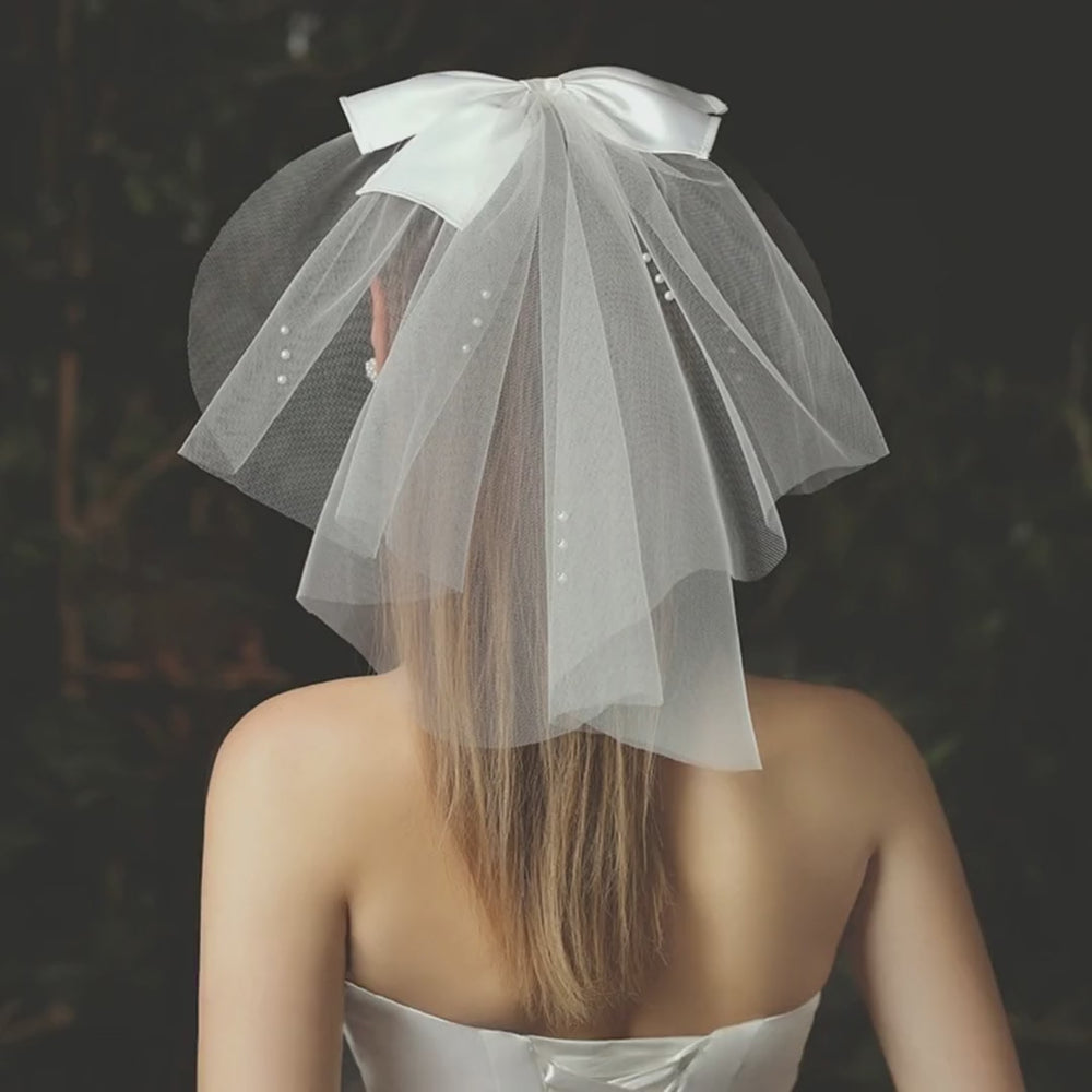 Model wearing the Juliette Pearl Bow mini bridal veil, showing its bow and pearl details.